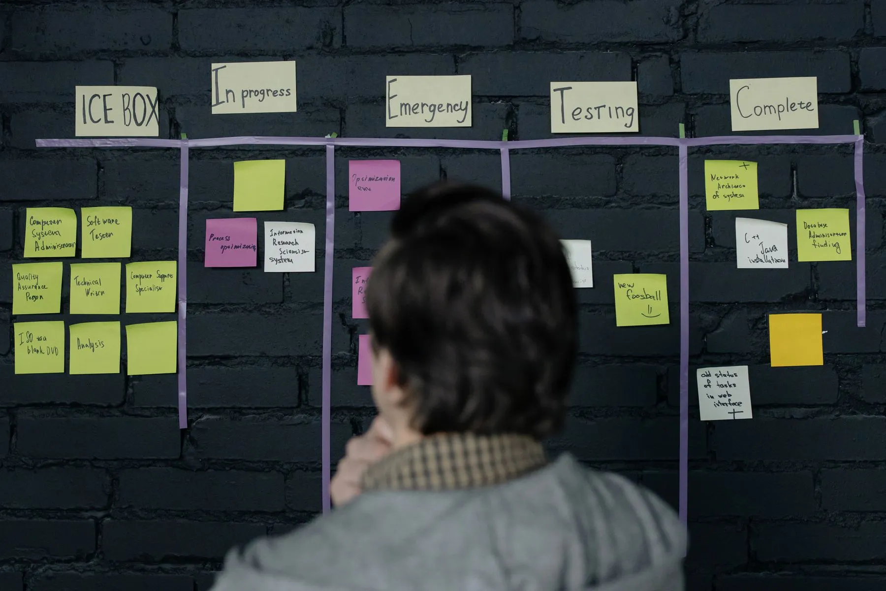 A project manager reviewing a task board of sticky notes